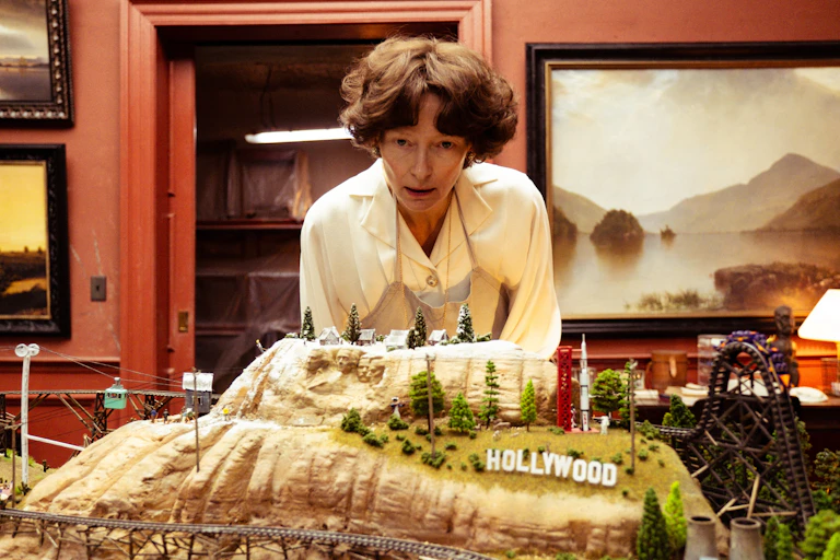 Tilda Swinton looking at a toy railway that has been designed after the Hollywood hills