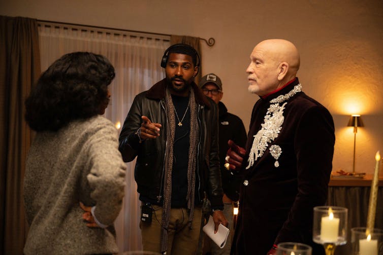 Two actors and a director discussing a scene on set.