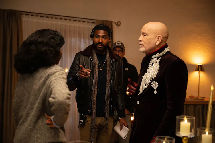 Two actors and a director discussing a scene on set.