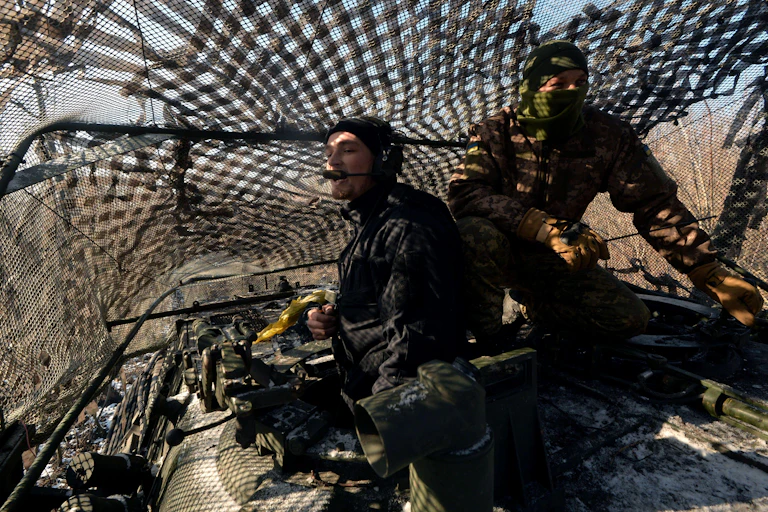 Two Ukrainian soldiers on a tank.