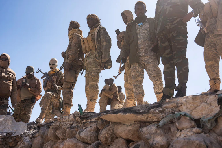 Men in combat uniforms, carrying weapons