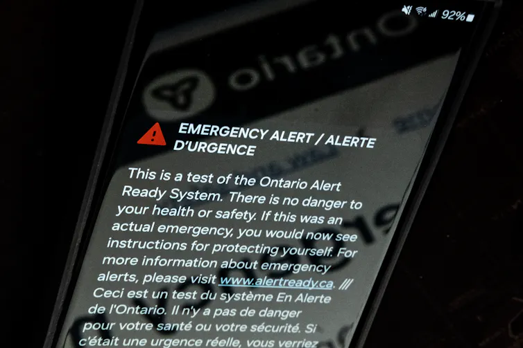 A phone showing an emergency alert text message sent from the Ontario government