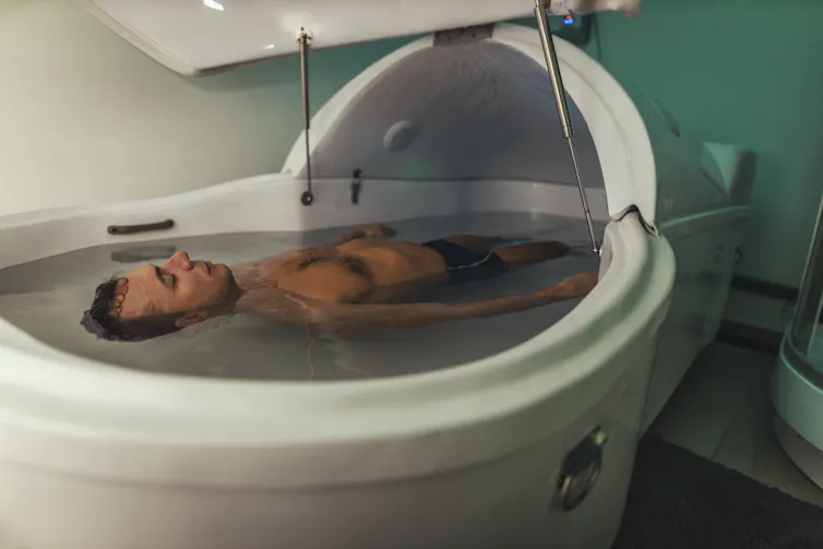 A man floats in a sensory deprivation tank.