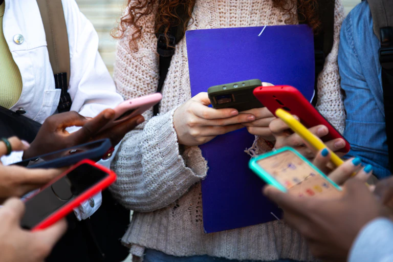 closeup of a group of people showing seven phones of different colors