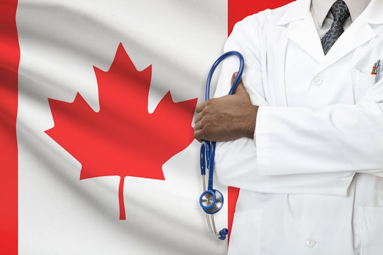 Cropped photo of a person in a white coat holding a stehoscope, with a Canadian flag in the background