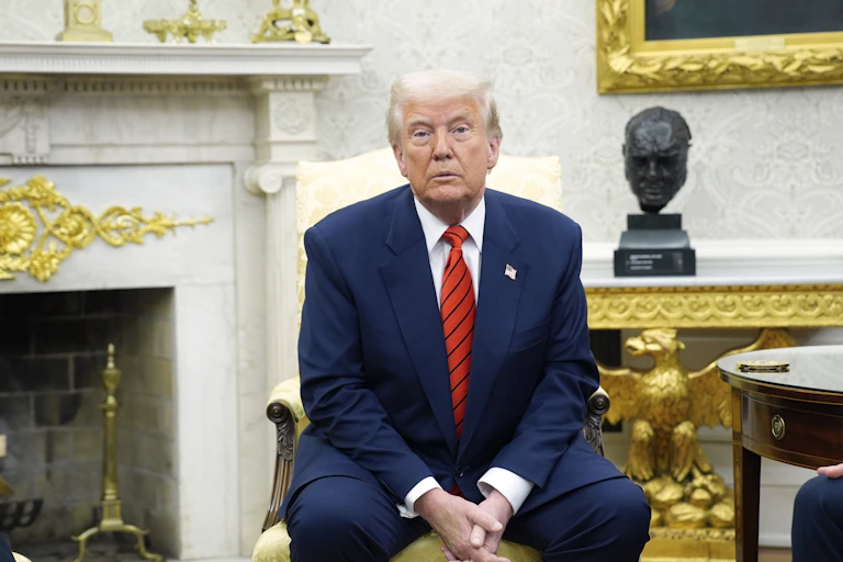 President Donald Trump sits on a chair in the White House.