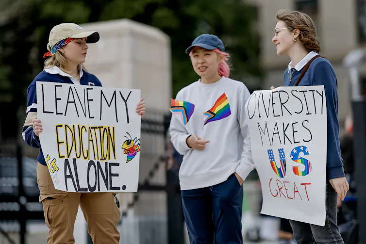 Young people holding signs reading 'leave my education alone'.
