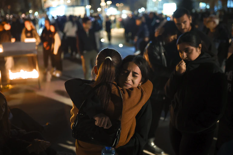 Two young women embracing in the wake of the fire at the