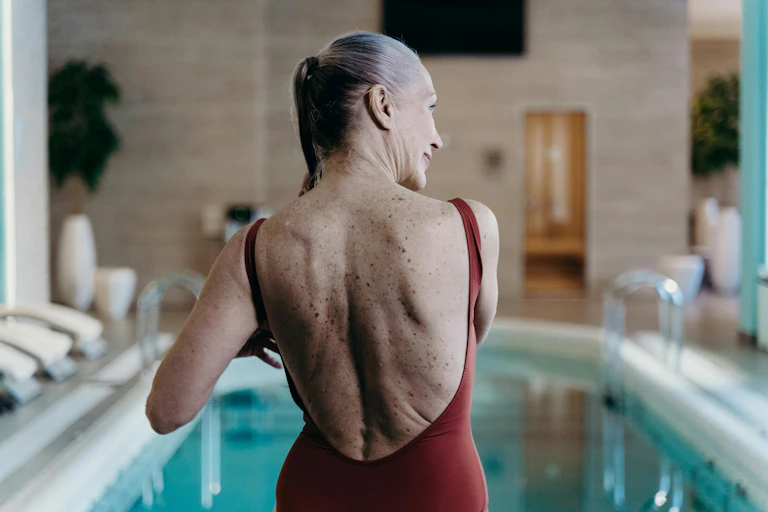 Woman with grey hair stands behind an indoor pool