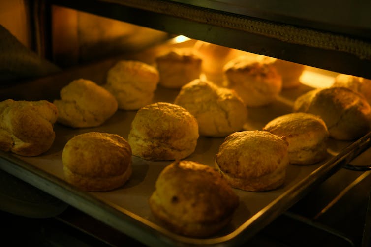 A tray of scones rising in a hot oven.