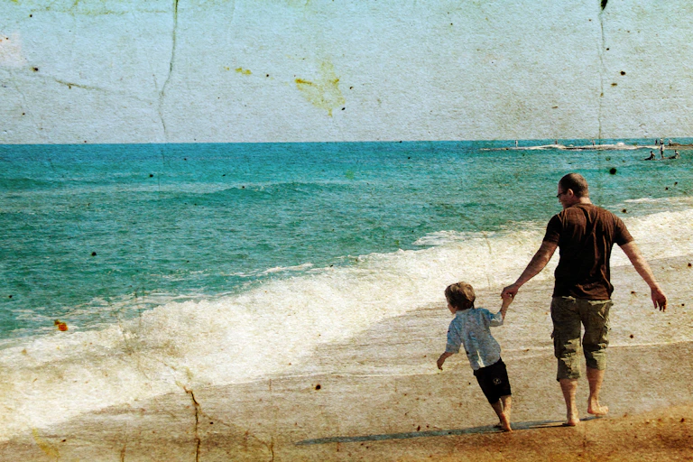 Un hombre y un niño pasean al lado de la orilla del mar, en una fotografía vintage.