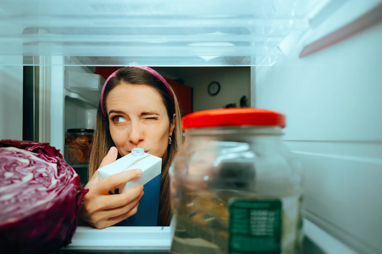 A woman looks in her fridge.