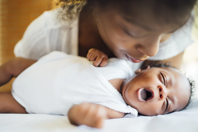 Woman bends closely over an infant