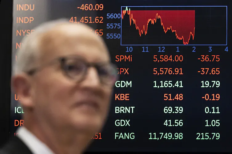 A screen shows the Dow Jones stock market index in decline.