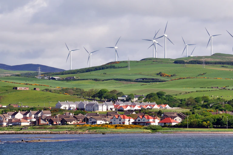 Wind farms on a hill with houses below.
