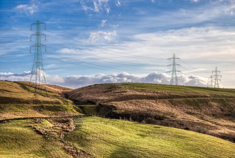Pylons and power lines in a hilly, rural landscape.