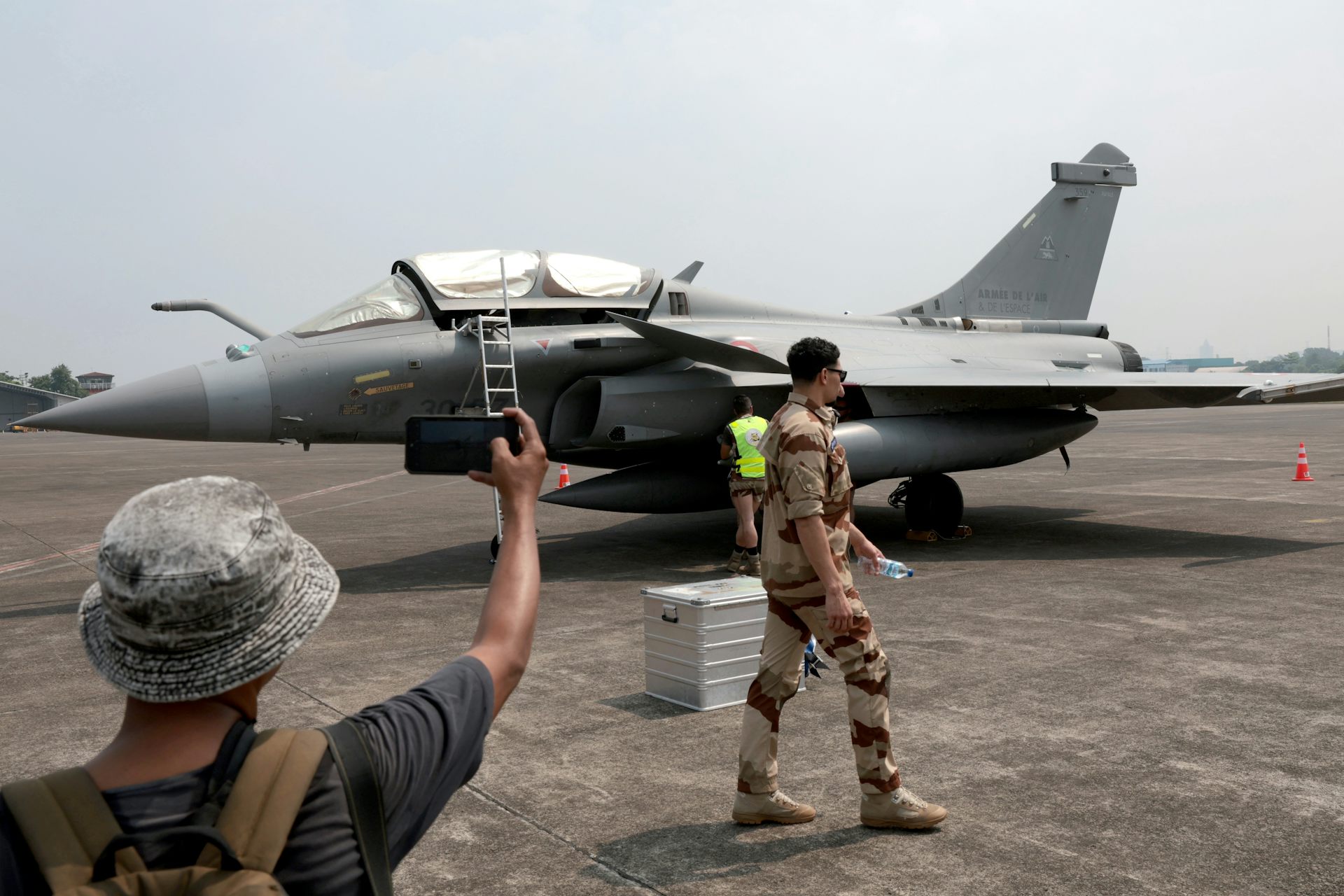 A man takes a photograph of a French Rafale fighter aircraft at an air base in Indonesia, July 2024.