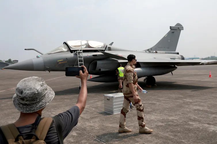 A man takes a photograph of a French Rafale fighter aircraft at an air base in Indonesia, July 2024.