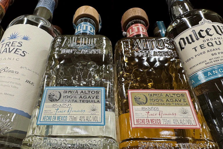 Four bottles of tequila on a shelf are photographed from below.
