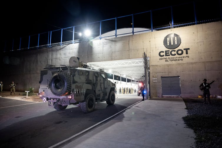 An armored vehicle outside a large concrete building.