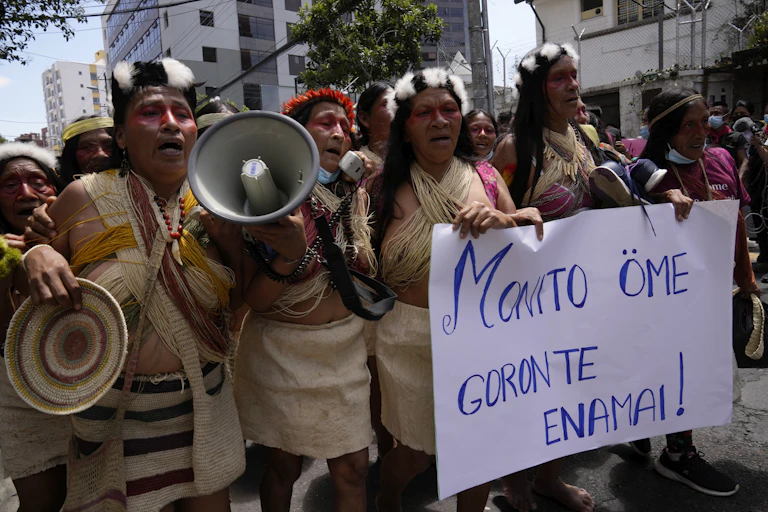 Indigenous people from the Amazon protests in the streets. They carry a sign that says: 'Our territory is not for sale,' which is written in Waorani.