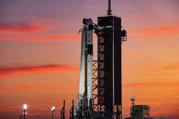 A rocket ready for launch backdropped by a purple and pink sky.