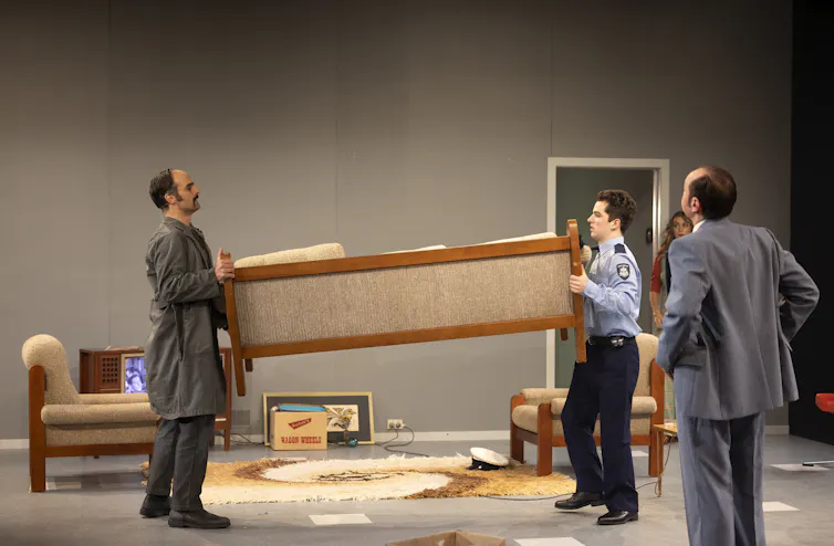 Two men hold either end of a couch.
