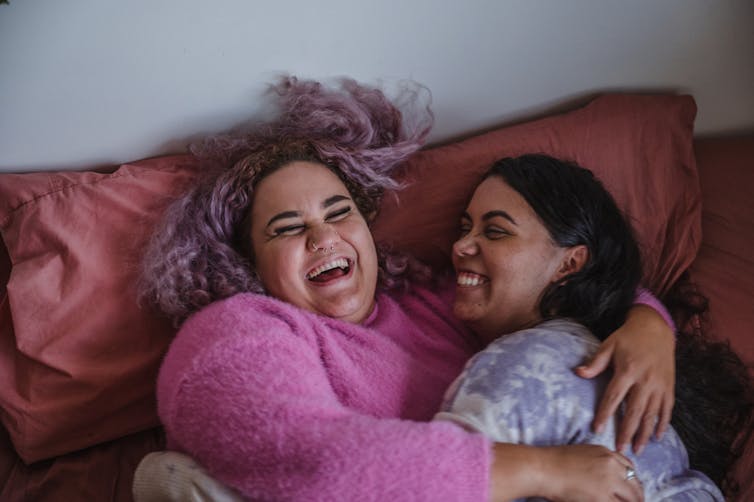 Two women happily embracing on a couch.