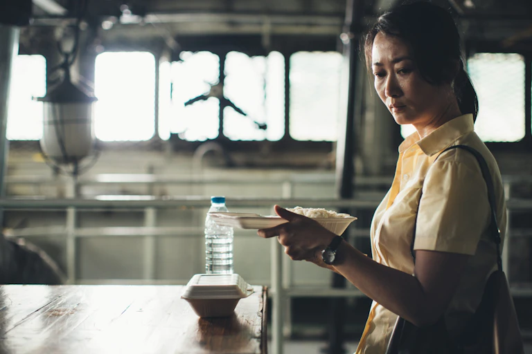A melancholy woman holds take-away food in her hands.