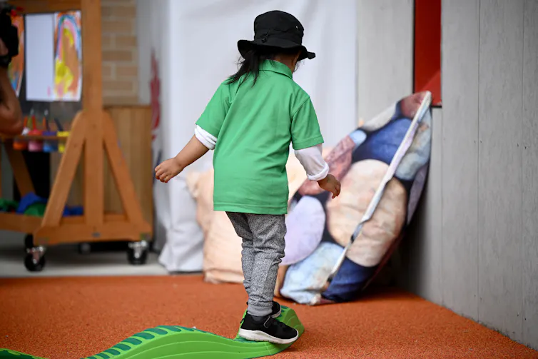 A young child walks in a childcare centre.