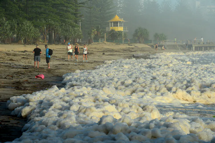ea foam is seen as walkers take to Burleigh Heads beach following wild weather caused by ex tropical Cyclone Oswald, Tuesday, Jan. 29, 2013.