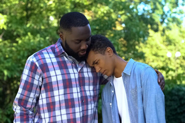 Father hugging sad teenage son