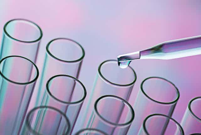 Glass pipette distributing liquid into test tubes.