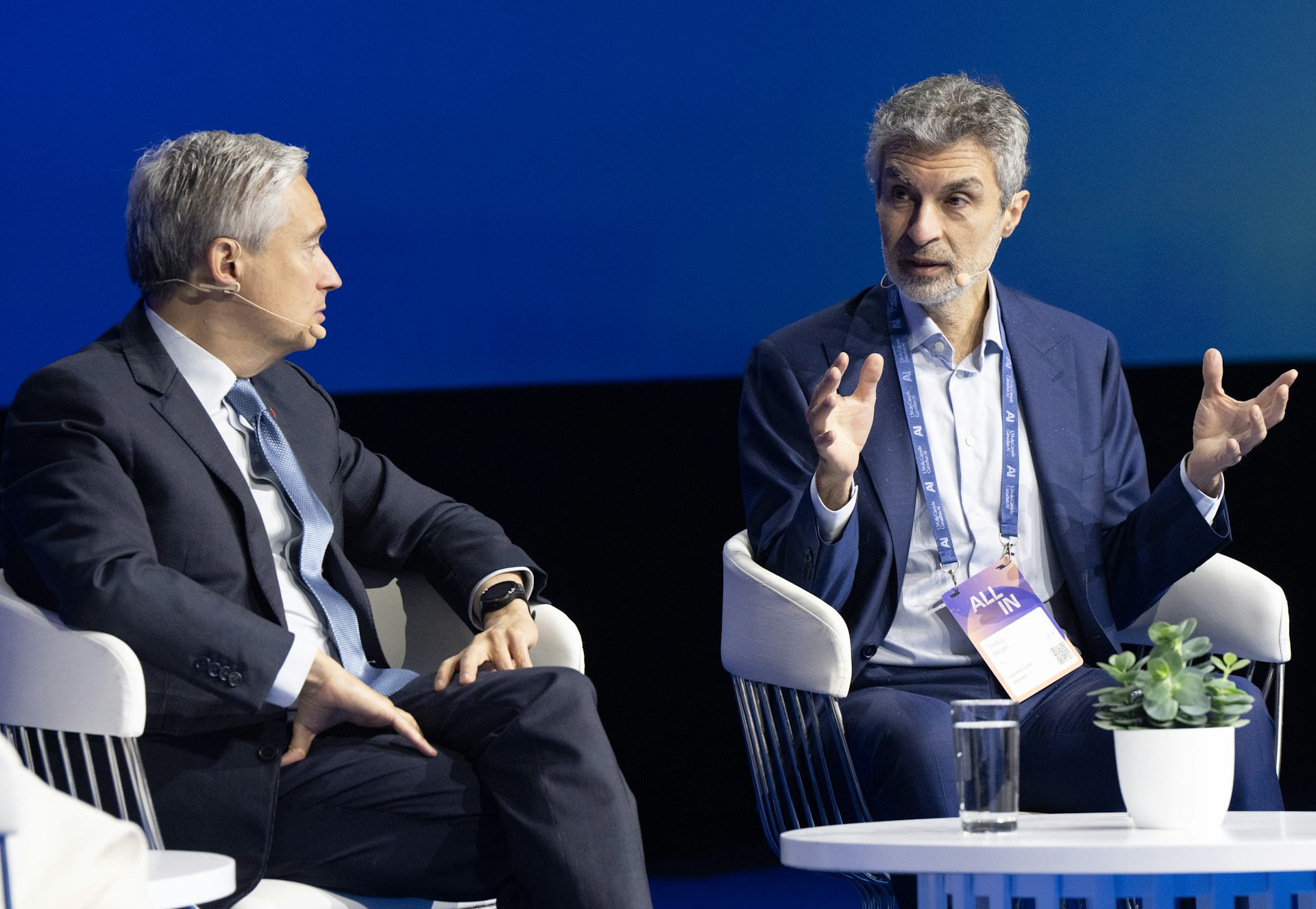 Yoshua Bengio, Canada's CIFAR AI Chair, sits in a chair on stage and speaks with Federal Industry Minister Francois-Philippe Champagne at a conference on AI.