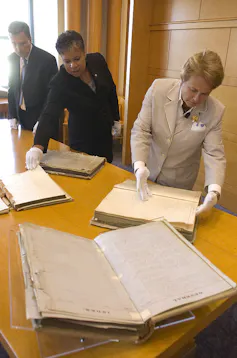 Two women and one man look through old books.