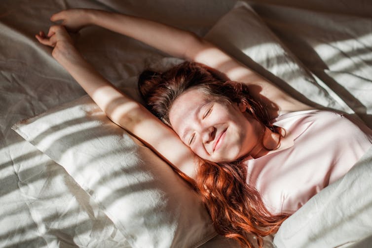 Woman waking up with sunlight on her face.
