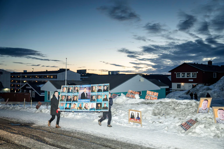 Demokraatit party members carry a poster with pictures of their candidates in the Greenland capital, Nuuk, March 2025.