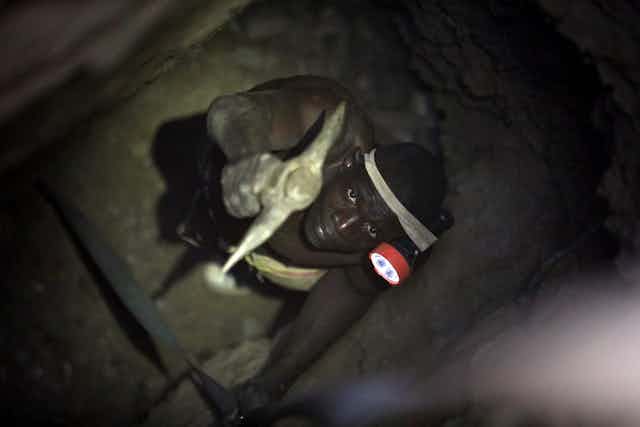 View from above of a man holding a pickaxe and wearing a torch strapped to his head