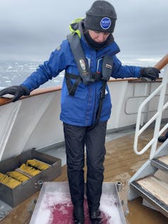 Woman on Antarctic ship stands in pink disinfectant boot wash station
