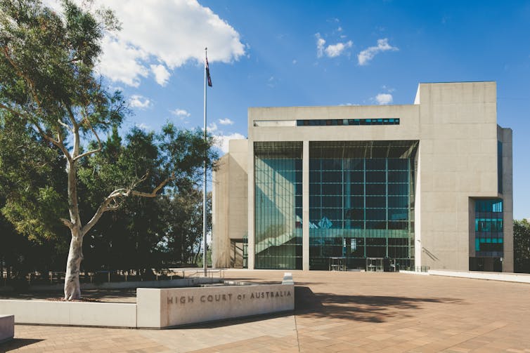 The exterior of a large concrete building against a blue sky