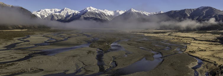 A braided river with snow capped mountains in the background.