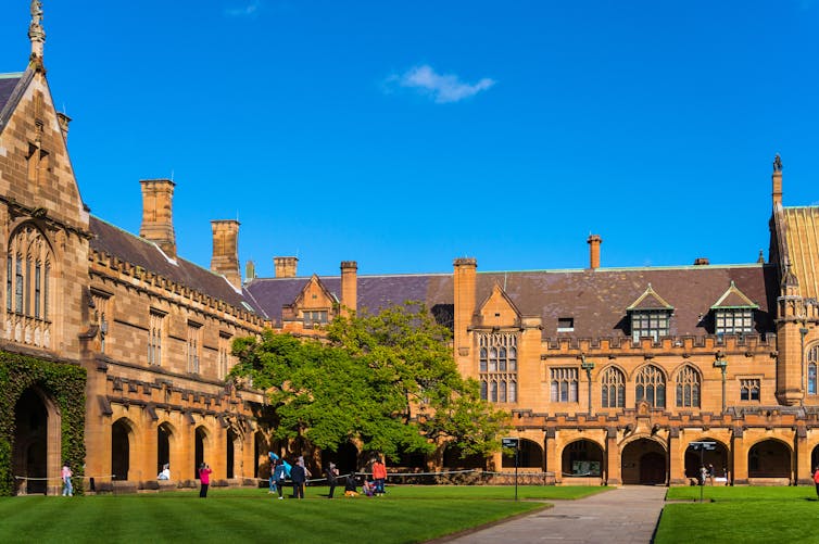 A sandstone quadrangle around a lush green lawn.