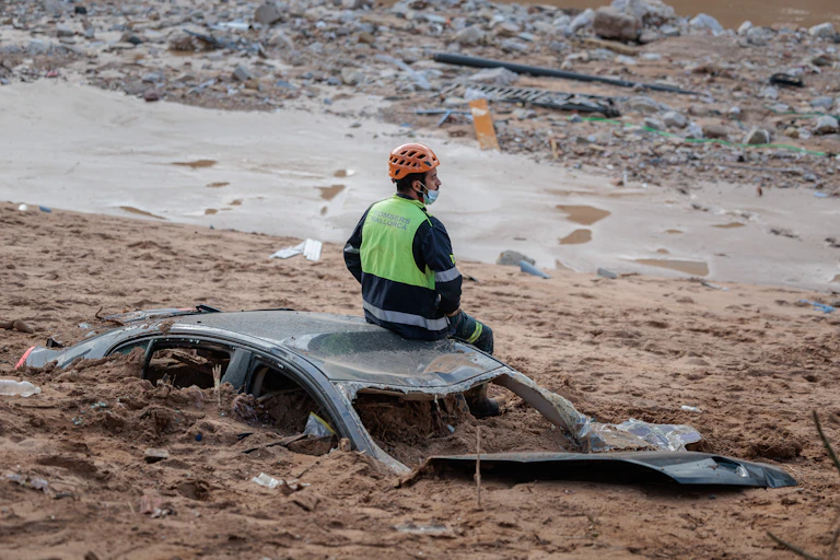 man sitting on car buried in mud.
