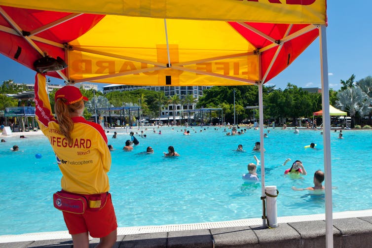 A lifeguard watches swimmers at a large pool.