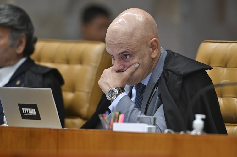 A man looks at his computer while sitting in his seat.