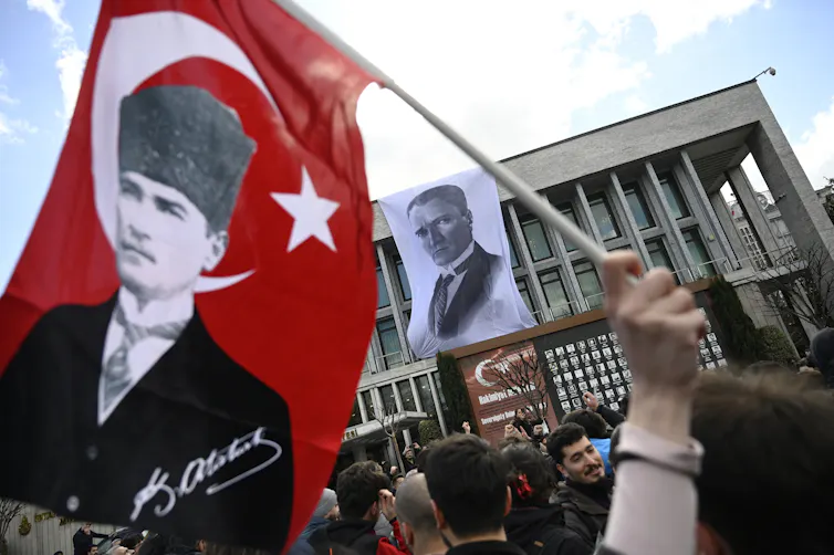 Protesters wave Turkish flags with a man's face on it.