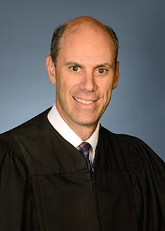 A balding man in a judge's robe.