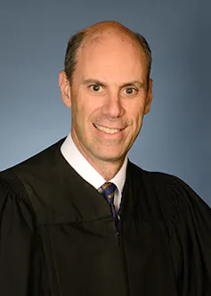 A balding man in a judge's robe.