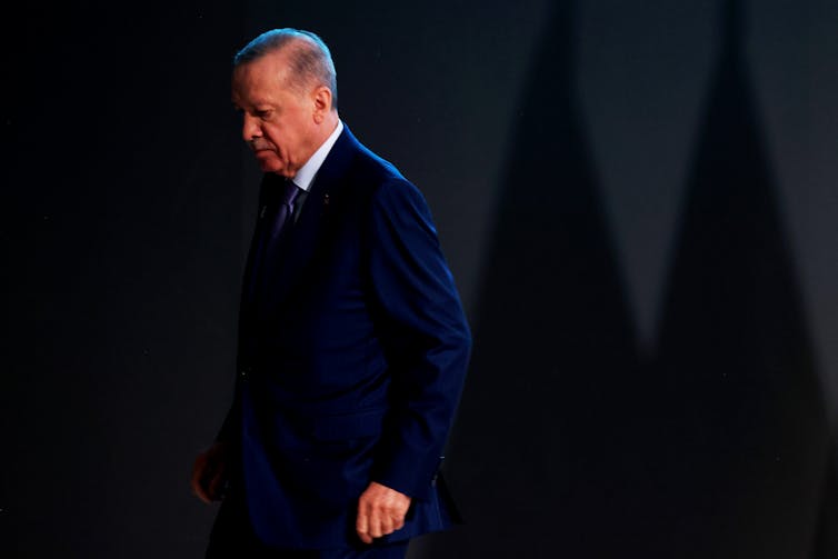 A man in a suit walks off a stage.