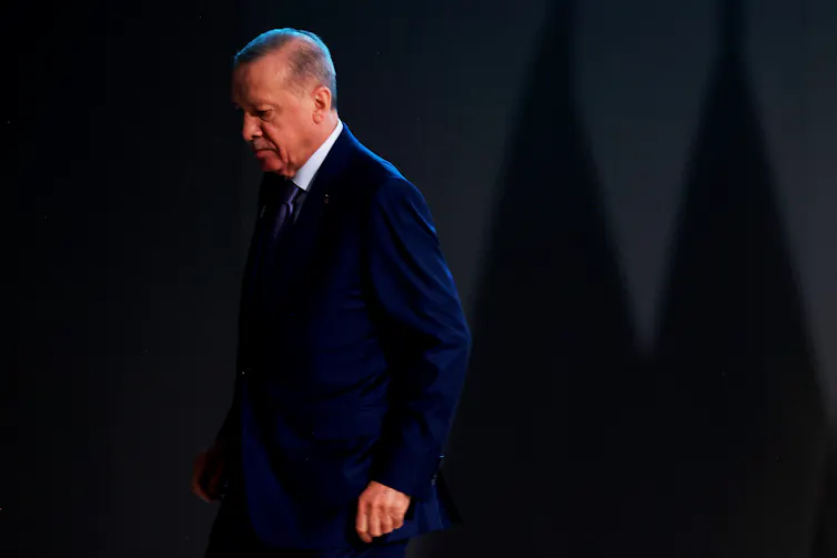 A man in a suit walks off a stage.